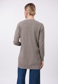 Light gray knit sweater with a round neckline and long sleeves. Features ribbed hem and cuff detailing. Worn with blue wide-leg pants.
