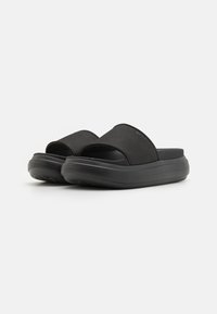 Infradito neri con una larga fascia in tessuto e suola testurizzata. Presentano una base spessa e imbottita per il comfort. Design semplice e moderno.