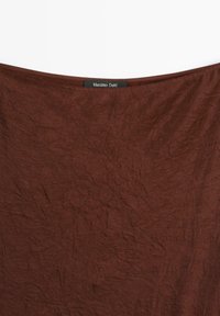 Hnědá zmačkaná látka s měkkou strukturou, v horní části se nachází černý štítek s nápisem "Massimo Dutti". Nejsou viditelné žádné výrazné vzory nebo akcenty.