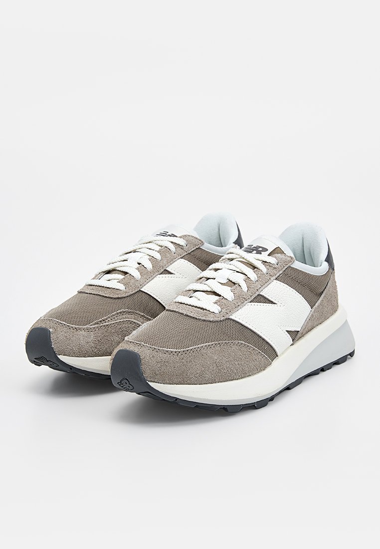 Graue und weiße Sportschuhe aus einer Mischung aus Wildleder und Mesh-Materialien, mit strukturierter Oberfläche, rundem Zehenbereich und gepolsterter Sohle.