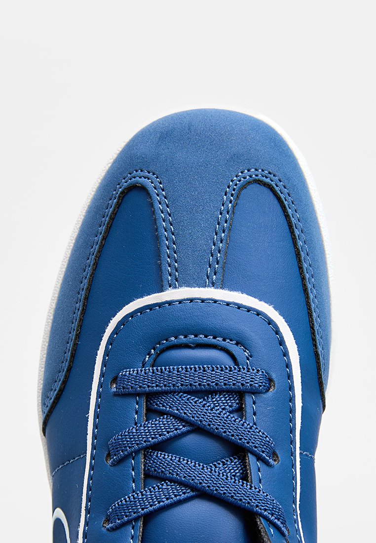 Baskets bleues avec une tige en cuir lisse, semelle en caoutchouc blanche, détails cousus, devant à lacets et accents blancs contrastants.