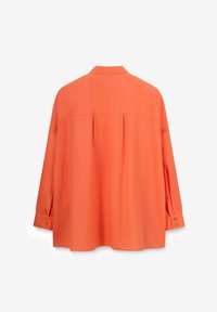 Chemise orange à manches longues en tissu léger, dotée d'un empiècement au dos et de plis, avec des poignets boutonnés et une coupe décontractée.