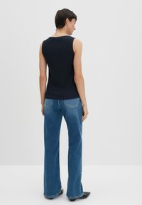 Top senza maniche a coste navy abbinato a jeans ampi a vita alta blu, caratterizzato da una consistenza liscia e un design minimalista.