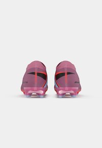 Un paio di scarpini da calcio Nike Mercurial rosa e rossi mostrati da dietro su uno sfondo bianco.