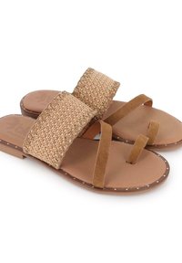 Sandalias marrones con tiras superiores de paja trenzada y lazo en ante para los dedos. Las suelas presentan una textura marrón claro con perforaciones decorativas.