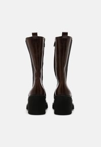 Bottines en cuir marron avec une finition brillante, dotées d'un bout arrondi, d'un talon noir épais et de fermetures éclair latérales pour un enfilage facile.
