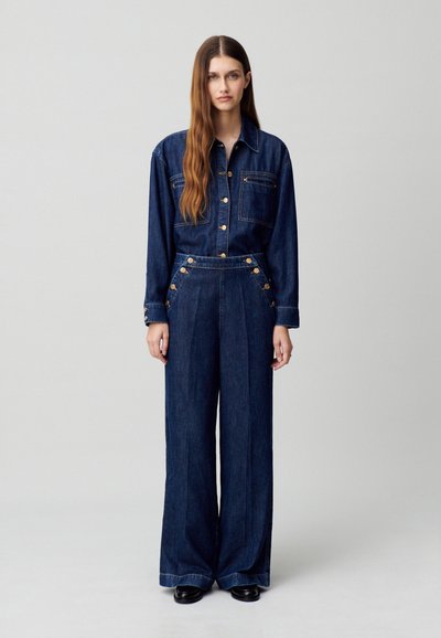 Conjunto de denim que incluye una camisa de botones y pantalones de pierna ancha de cintura alta. Color azul oscuro, acentos en hardware dorado y bolsillos frontales.