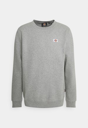 Harmaa college-paita puuvillasekoitetta, pyöreä kaula-aukko, resorikaitaleet hihoissa ja helmassa. Rintamuksessa pieni logopatch. Yksinkertainen ja tekstuuri pintakuvio.