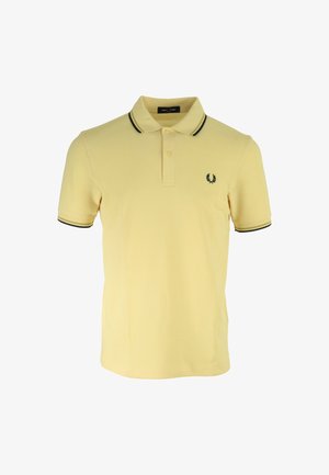 Polo amarillo de algodón, con un cuello ribeteado en negro, tapeta de dos botones y un pequeño logo bordado en el pecho.