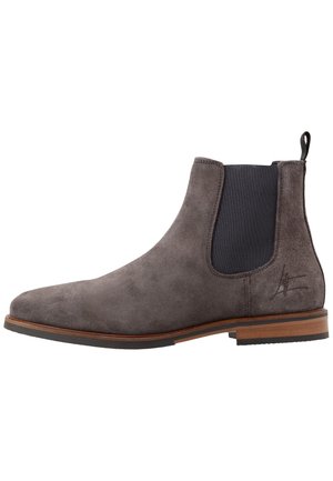 Bottine Chelsea en daim gris avec panneau latéral élastique noir, semelle en bois et languette à l'arrière.