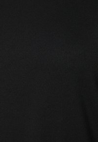 Mustan neulotun kankaan sileä pinta ja hieno ribbikuvio, joka näyttää tasaisen ja yhtenäisen kuvion pinnalla.