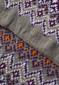 Tessuto lavorato a maglia caratterizzato da un motivo geometrico con accenti viola, bianchi e arancioni su uno sfondo grigio. Finitura testurizzata con forme variate.