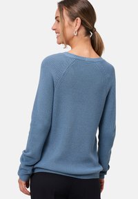 Blauw gebreid sweater met een tekstuurpatroon, ronde halslijn en raglanmouwen. Heeft een ontspannen pasvorm en geribde manchetten.