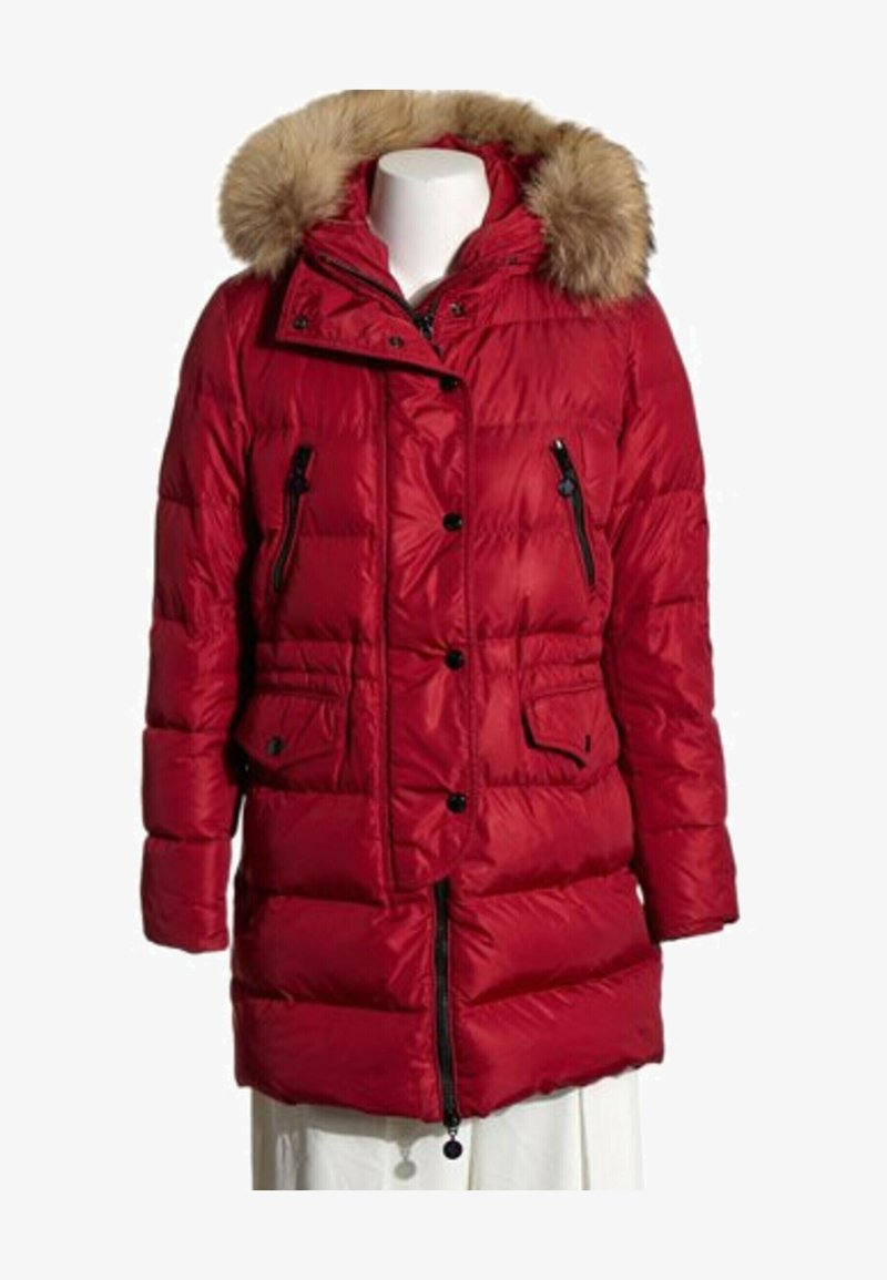 Manteau d’hiver matelassé rouge jusqu’aux genoux avec capuche bordée de fourrure, fermeture éclair noire et boutons, et quatre poches avant sur un mannequin blanc.
