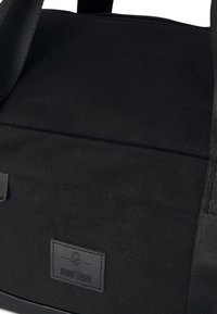 Černá plátěná taška s pevným designem. Má obdélníkový tvar, hladký povrch a viditelnou nášivku loga na straně.