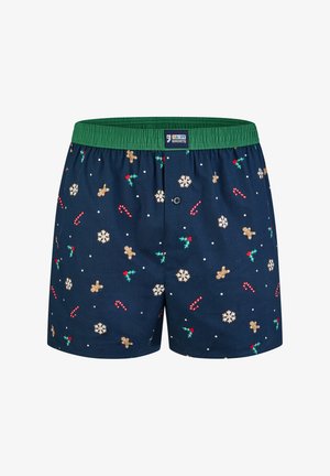 Marineblauwe boxershorts met een groene elastische tailleband, versierd met een feestelijk patroon van peperkoekmannetjes, sneeuwvlokken, zuurstokken, hulst en kleine stippen.