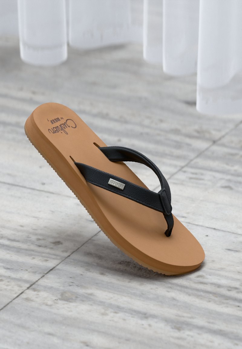 Καφέ σαγιονάρα με μαύρα λουριά που βρίσκεται πάνω σε γκρι πλακάκια δαπέδου, με λευκές κουρτίνες να κρέμονται στο παρασκήνιο.