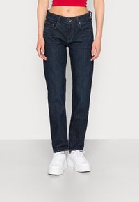 Mörkblå denimjeans med rak passform, fem fickor och knappstängning, tillsammans med vita platåsneakers.