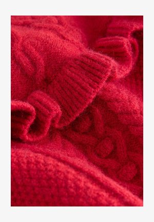 Piros kötött pulóver texturált mintákkal, bordás mandzsettákkal és puha, bolyhos befejezéssel. Az élénk piros szín hangsúlyos használata az egész darabon.