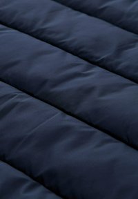 Navy quilted fabric with a puffy texture, featuring horizontal lines created by quilted sections, smooth surface, and no visible patterns or hardware.