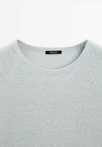 Vaaleanharmaa pitkähihainen paita, jossa on pyöreä kaula-aukko ja raglan-hihat. Valmistettu pehmeästä kankaasta, jonka pinta on sileä ja tasainen. Brändilogo näkyvissä.