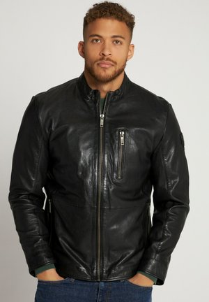 Chaqueta de cuero negra con cuello alto, cremallera frontal y bolsillo en el pecho con cremallera. Presenta mangas ajustadas y una textura suave.