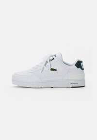Białe skórzane trampki z zaokrąglonym noskiem, sznurowanym zapięciem i zielonymi akcentami. Zawierają perforowane detale oraz logo Lacoste po boku.