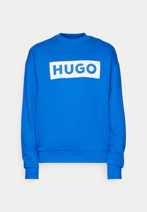 Blaues Sweatshirt aus glattem Material mit Rundhalsausschnitt, versehen mit einem großen weißen rechteckigen Grafik, auf der der Text "HUGO" steht. Lange Ärmel.