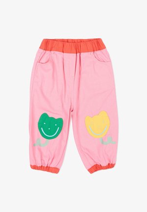 Pantalon rose pour enfant avec taille et poignets élastiques orange, ornés de patchs de fleurs souriantes vertes et jaunes sur les genoux.