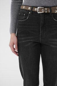 Mustad teksapüksid, millel on kõrge vöökoht, tuhmunud tekstuur ning pruun vöö, millel on hõbedased naelad ja metallist pannal.