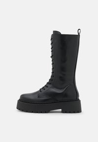 Bottes en cuir noir jusqu'au genou avec une semelle en caoutchouc robuste, un devant à lacets, des détails brodés et une languette en haut.