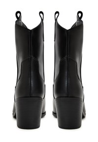 Bottines en cuir noir avec une texture lisse, un talon effilé, des tirettes et des découpes latérales distinctes pour un enfilage facile.