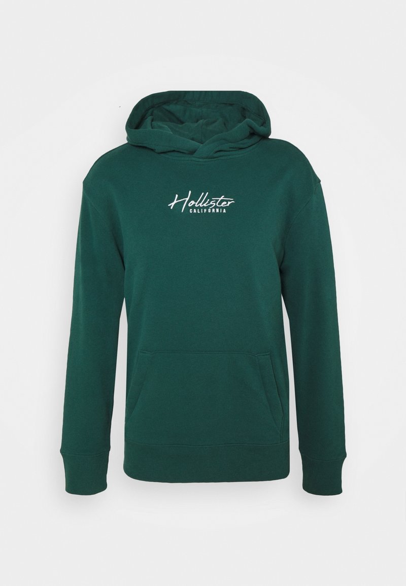 Mörkgrön munkjacka med huva, framficka och vitt "Hollister California"-logotyp på bröstet, visas mot en vit bakgrund.