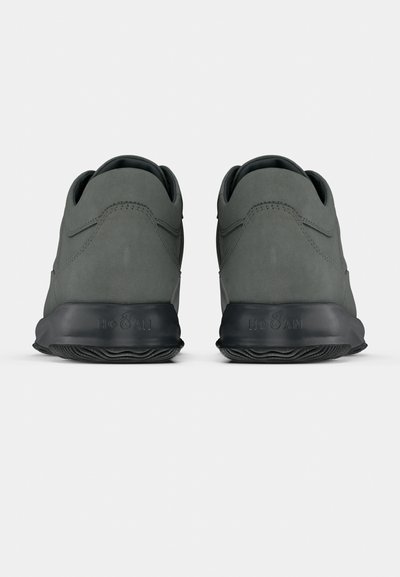 Grå ruskindssneakers med en glat finish, rund form og sorte gummisåler. Har diskrete syninger og et logo på hælen.