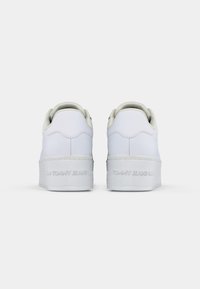 Weiße Sneaker mit einer glatten, lederartigen Oberseite, gepolsterter Knöchelpartie und strukturiertem Gummisohle. "TOMMY JEANS" auf der Ferse geprägt. Klassisches Schnürdesign.