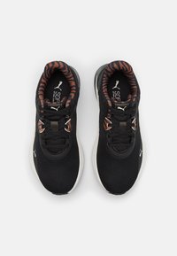 Scarpe da ginnastica nere con una tomaia testurizzata, caratterizzate da un colletto a strisce arancioni e nere. Suola bianca con dettagli del logo. Lacci chiusi.