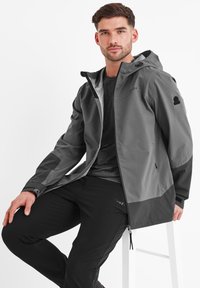 Gray waterproof jacket with a hood, black accents, and zippered pockets, paired with black pants. Features smooth, textured fabric.