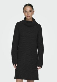 Robe noire en tricot avec col camionneur, présentant un motif texturé, des manches longues et un ourlet côtelé. Offre une coupe ample et confortable.