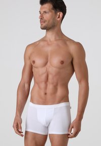 Boxer brief in cotone bianco con design senza cuciture, vita elasticizzata e una vestibilità aderente che esalta la forma. Tessuto liscio e leggero.