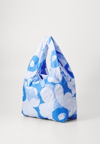 Blue reusable bag made of fabric featuring large white floral patterns, with two handles and a soft texture. Lightweight and spacious design.