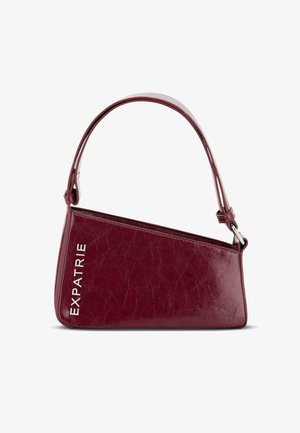 Burgundské kožené kabelka z imitácie kože s ostrým dizajnom, s striebornými kovovými detailmi a embosovaným textom "EXPATRIE" na boku.