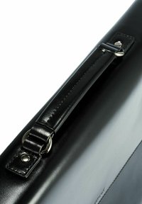 Czarna skórzana teczka z połyskiem, posiadająca wzmocniony uchwyt i metalowe okucia, podkreślająca trwałość i elegancki design.