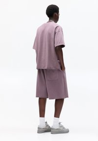 Overweldigend lavendelkleurig katoenen t-shirt met korte mouwen, gecombineerd met bijpassende shorts met zijzakken en rauwe randen. Sneakers met een grijze afwerking.