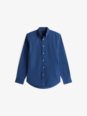 Tummansinihyinen napitettavassa paidassa on pitkät hihat, kapeahko malli, kaareva helma ja pieni logo vasemmassa rinnassa. Kankaan pinta on sileä.