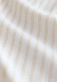 Tissu léger et texturé avec des rayures verticales alternées de blanc et de beige doux, doté d'une finition lisse et d'un subtil éclat.