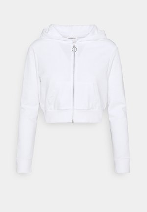 Sweat à capuche court blanc en tissu doux avec fermeture éclair, poches avant et capuche à cordon. Manches longues avec poignets côtelés.