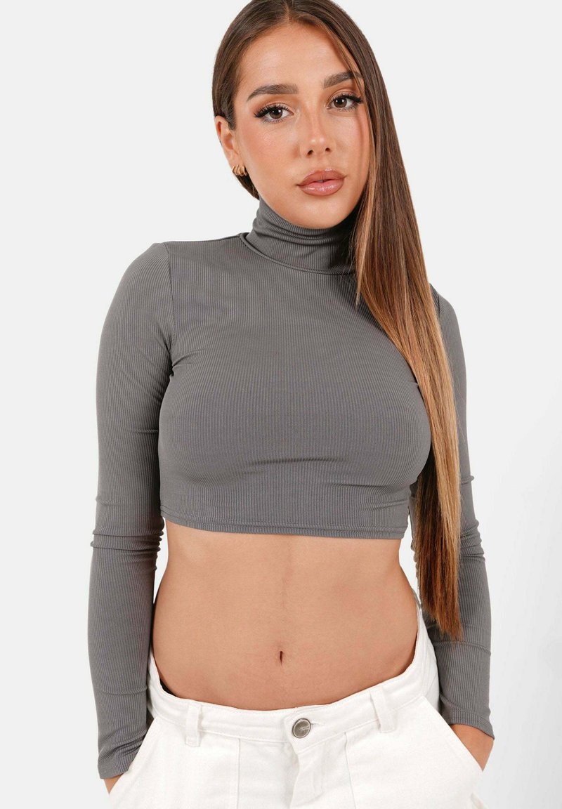 Grårutigt turtleneck kort topp med långa ärmar, med en åtsittande design och mjuk textur. Bärs med höga vita byxor.