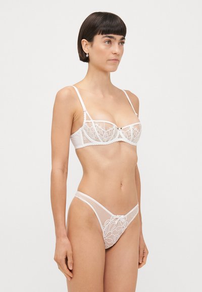 Witte lingerieset met kanten cups met bloemmotieven, verstelbare bandjes en doorzichtige panelen. Inclusief bijpassende string met strikdetail.