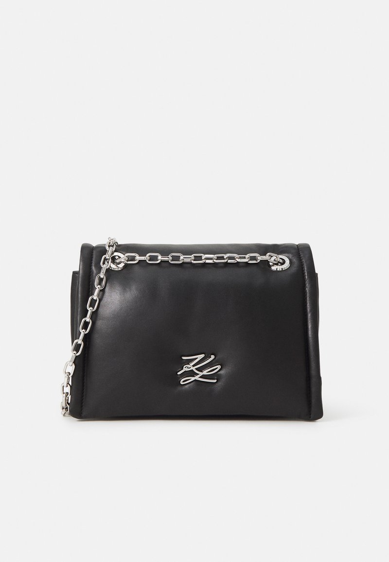 Black leather handbag with a silver chain strap, featuring a prominent logo on the front, smooth texture, and structured design.