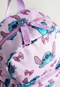 Fialový látkový batoh s postavičkou Disneyho Stitch a růžovými vzory mašlí. Dvojité zipové uzavírání s fialovými zipy a vrchním držadlem.